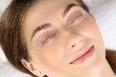 Photo of Woman undergoing eyelash laminating procedure in beauty salon, closeup