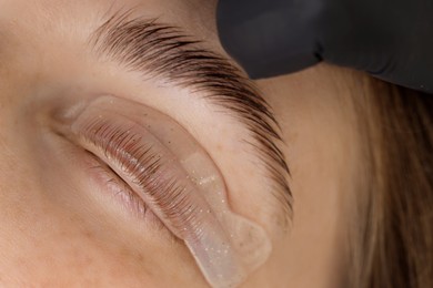 Photo of Woman undergoing eyelash laminating procedure in beauty salon, closeup