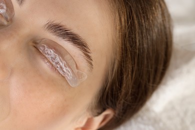 Photo of Woman undergoing eyelash laminating procedure in beauty salon, closeup