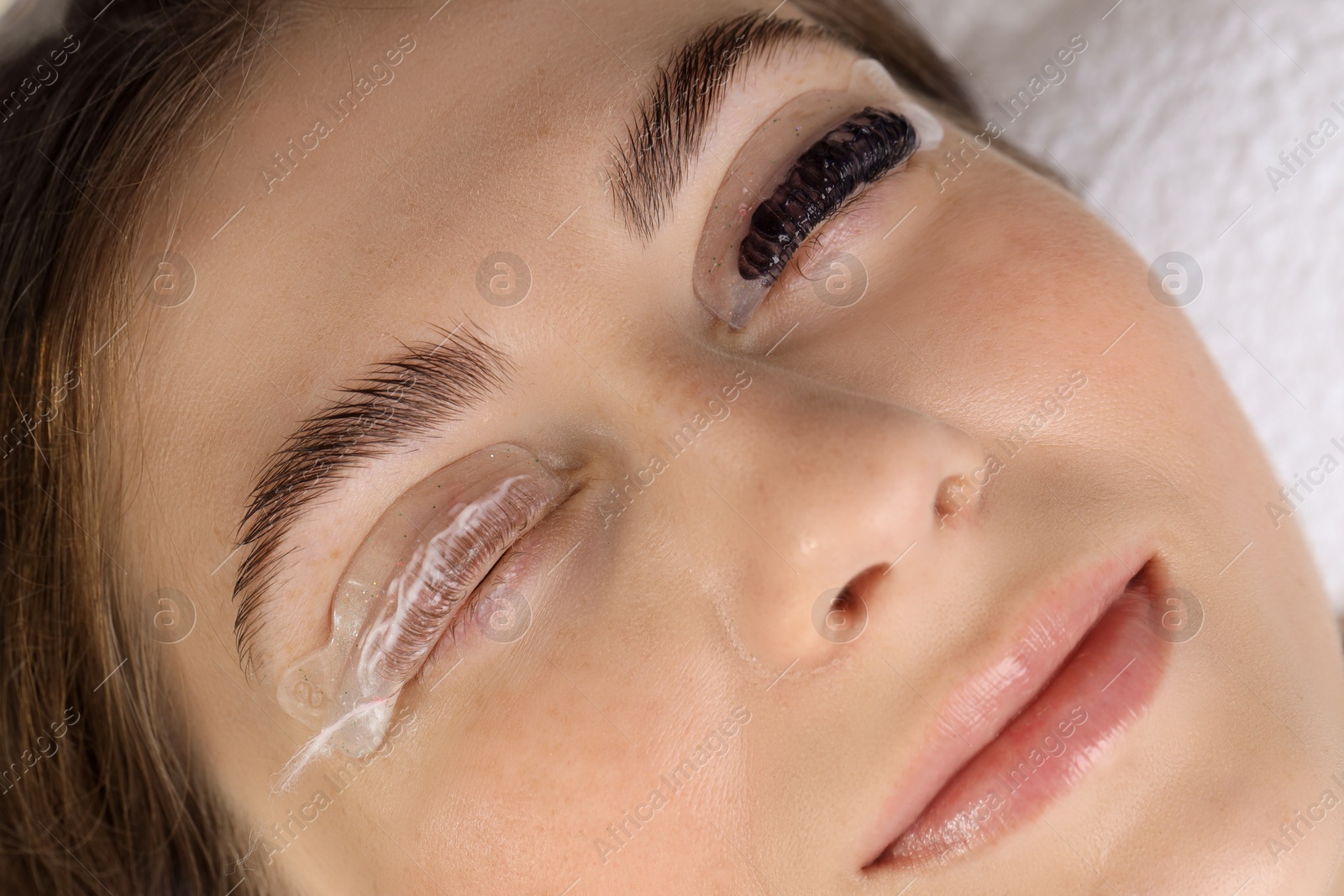 Photo of Woman undergoing eyelash laminating and tinting procedure in beauty salon, closeup