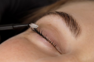 Photo of Brushing woman's lashes after lamination procedure, closeup