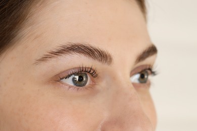 Photo of Beautiful woman after lash laminating and tinting procedure on light background, closeup