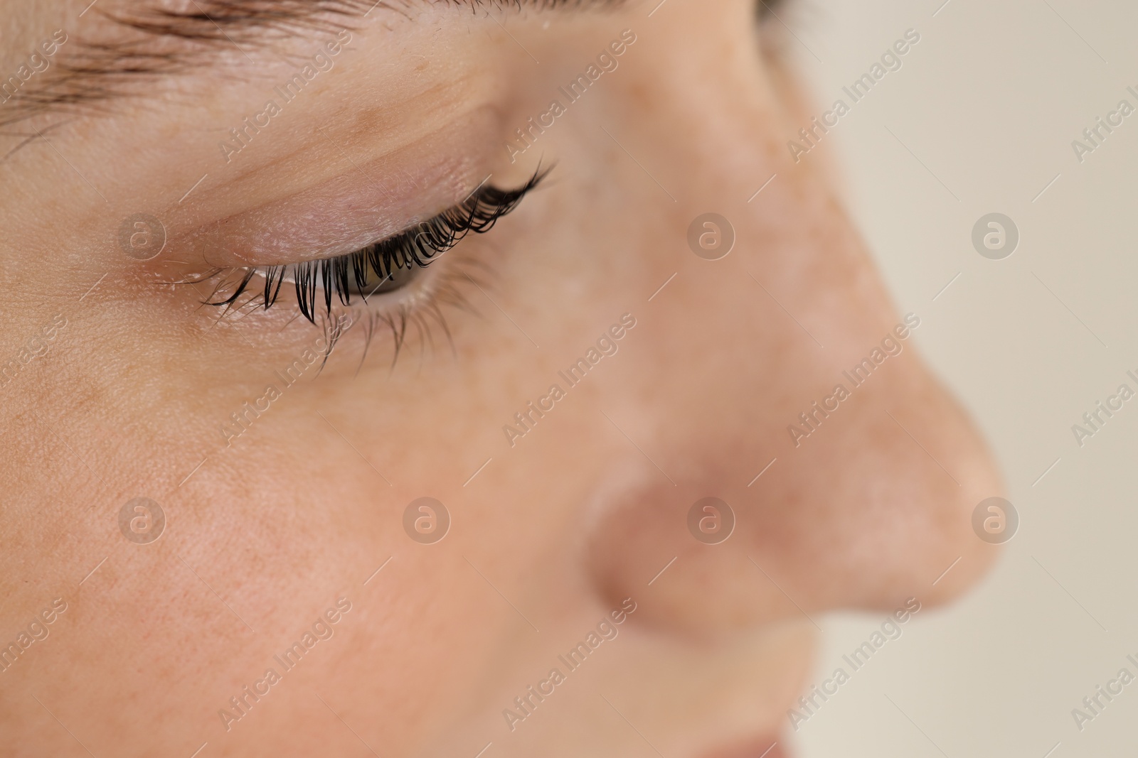 Photo of Beautiful woman after lash laminating and tinting procedure on light background, closeup