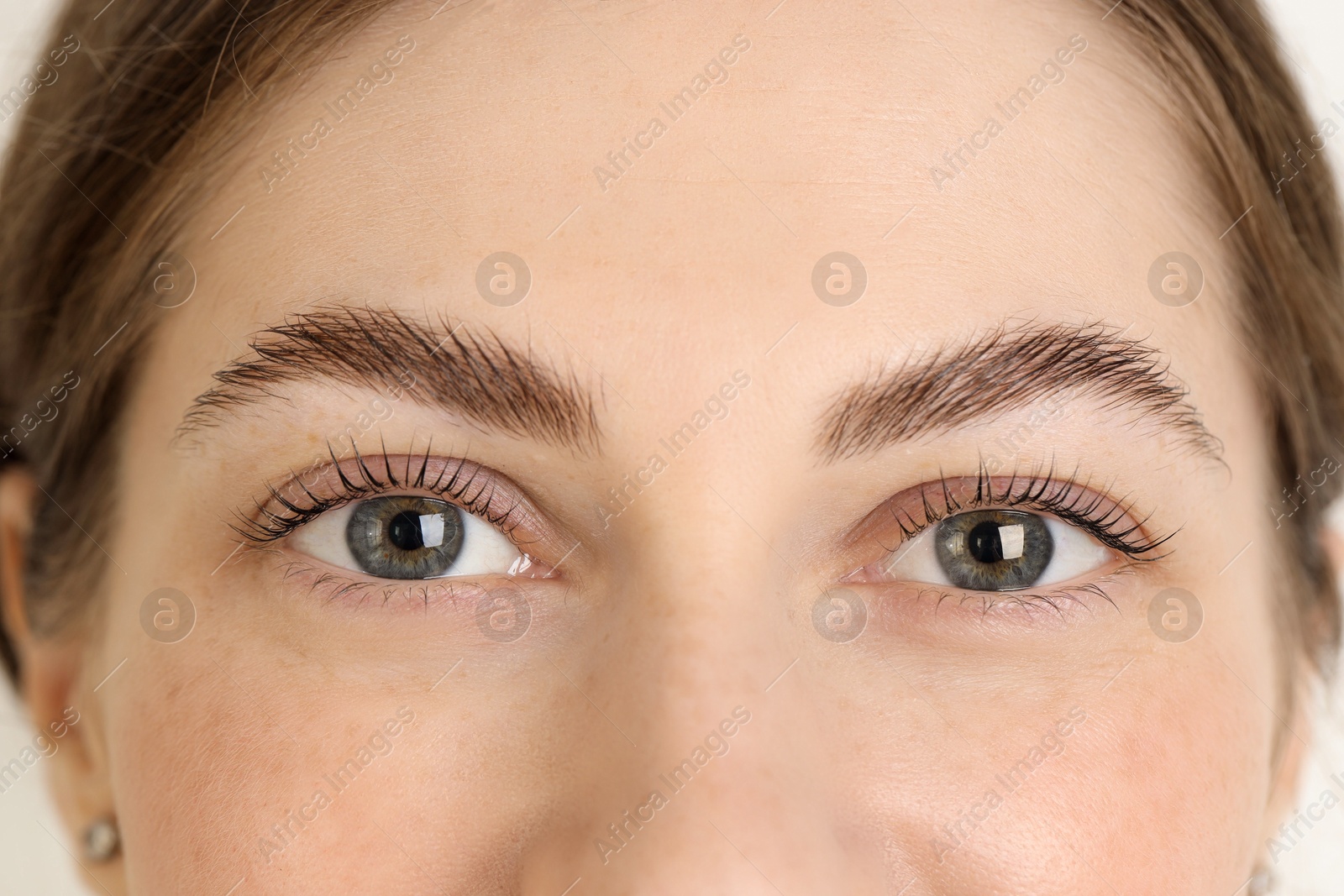 Photo of Beautiful woman after lash laminating and tinting procedure on light background, closeup