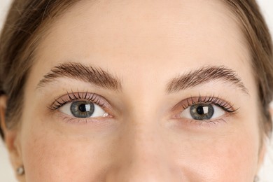 Photo of Beautiful woman after lash laminating and tinting procedure on light background, closeup