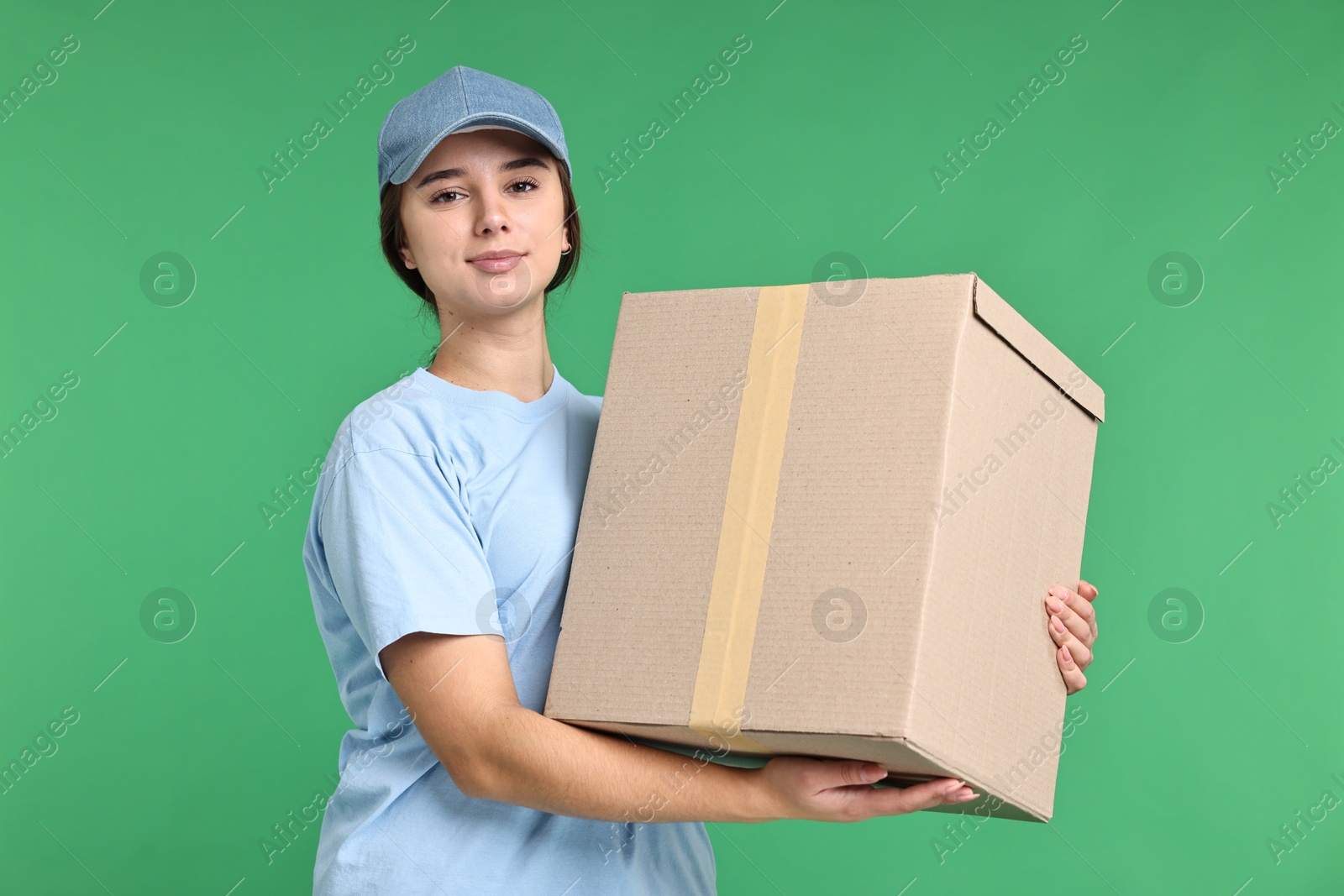 Photo of Girl in uniform with parcel on green background. Work for teenagers