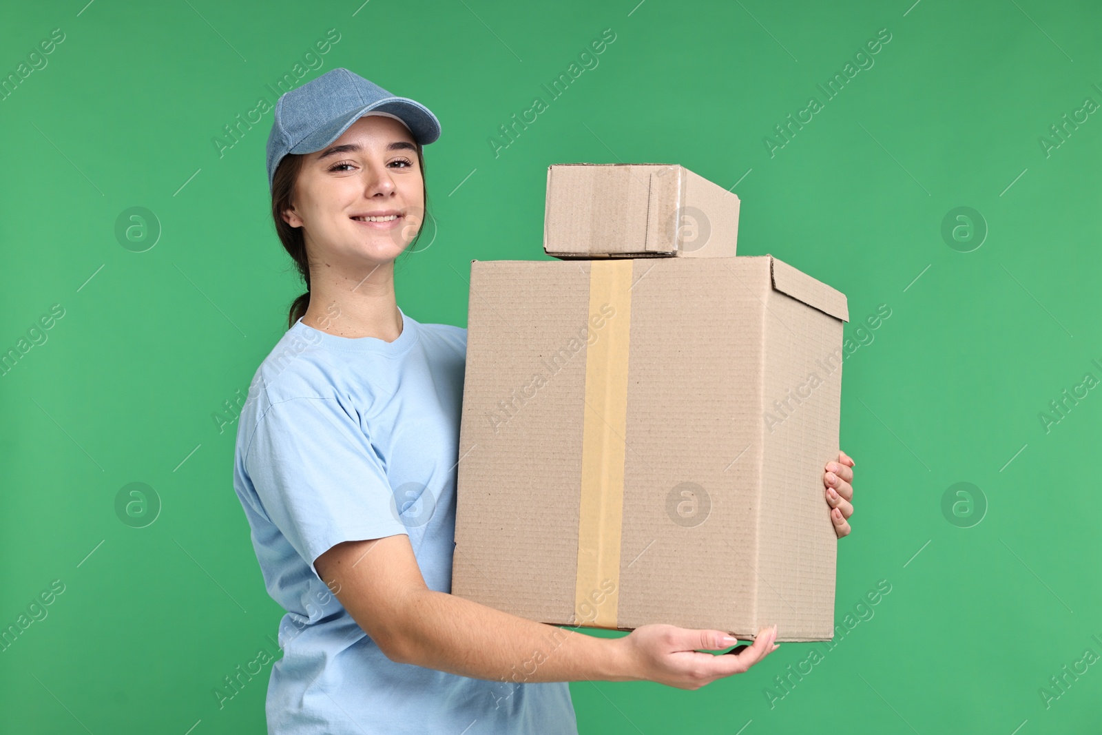 Photo of Girl in uniform with parcels on green background. Work for teenagers