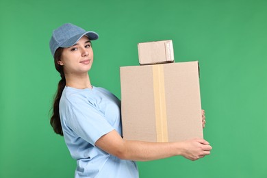 Photo of Girl in uniform with parcels on green background. Work for teenagers