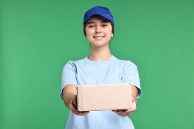 Photo of Girl in uniform with parcel on green background. Work for teenagers