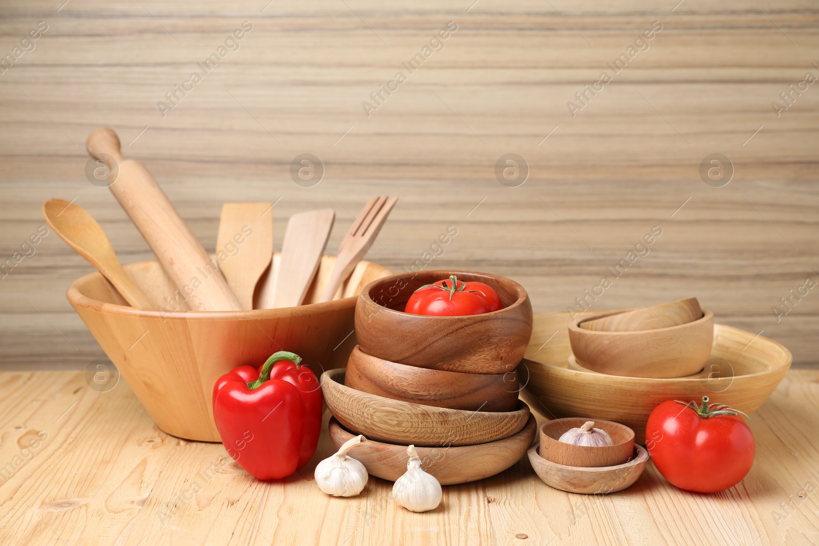 Photo of Dishware and cooking utensils with vegetables on wooden table