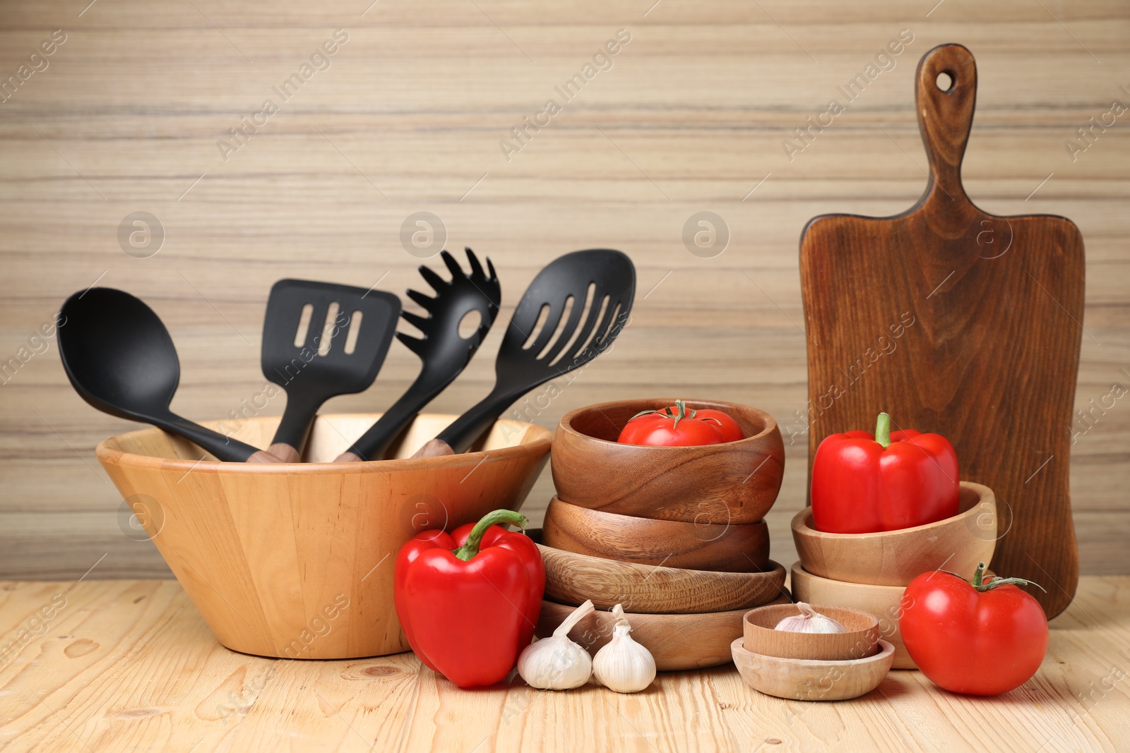 Photo of Dishware and cooking utensils with vegetables on wooden table