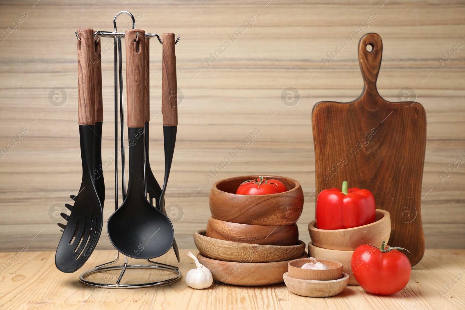 Photo of Dishware and cooking utensils with vegetables on wooden table