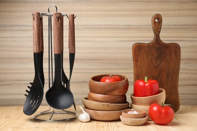 Photo of Dishware and cooking utensils with vegetables on wooden table