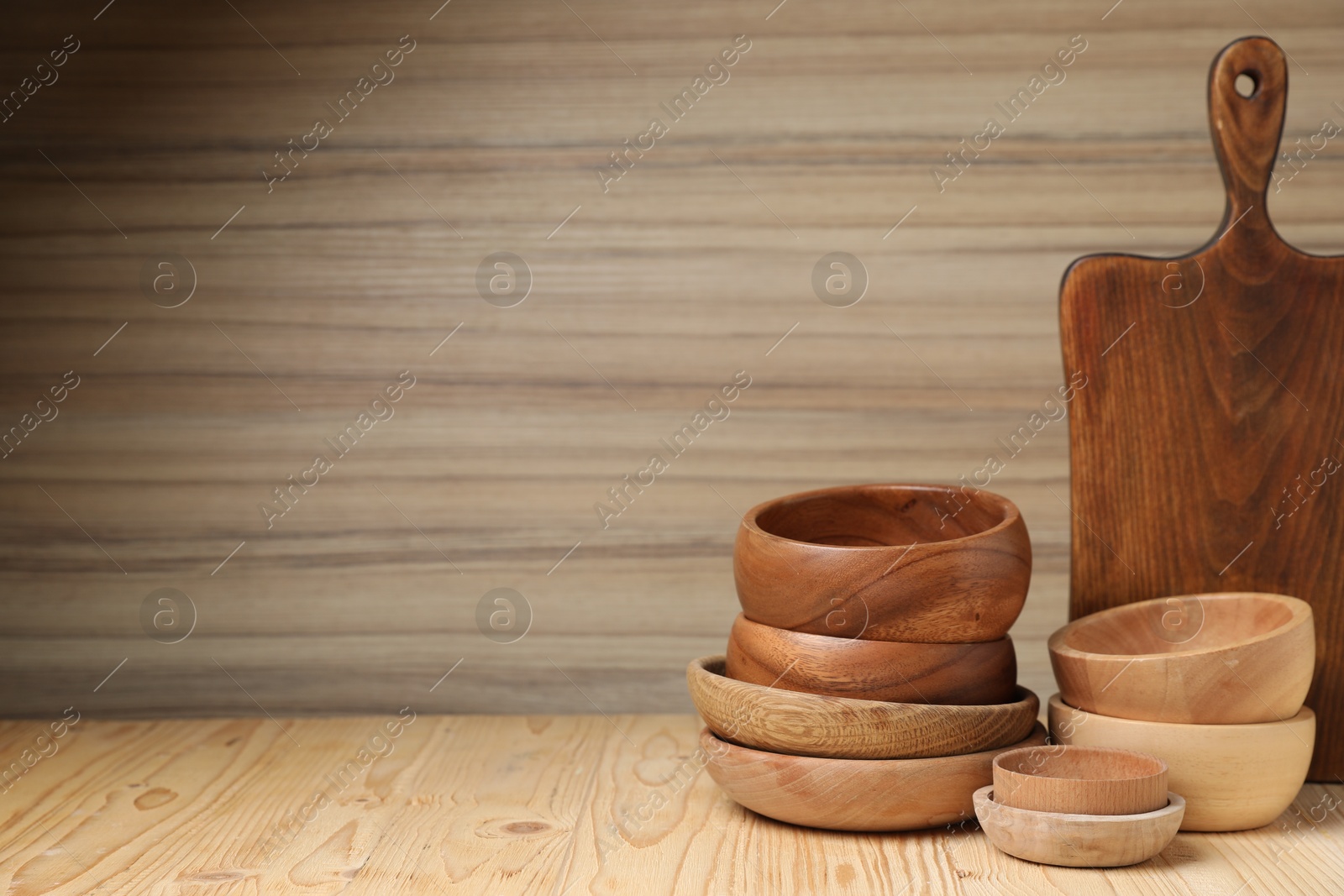 Photo of Bowls and cutting board on wooden table, space for text. Cooking utensils