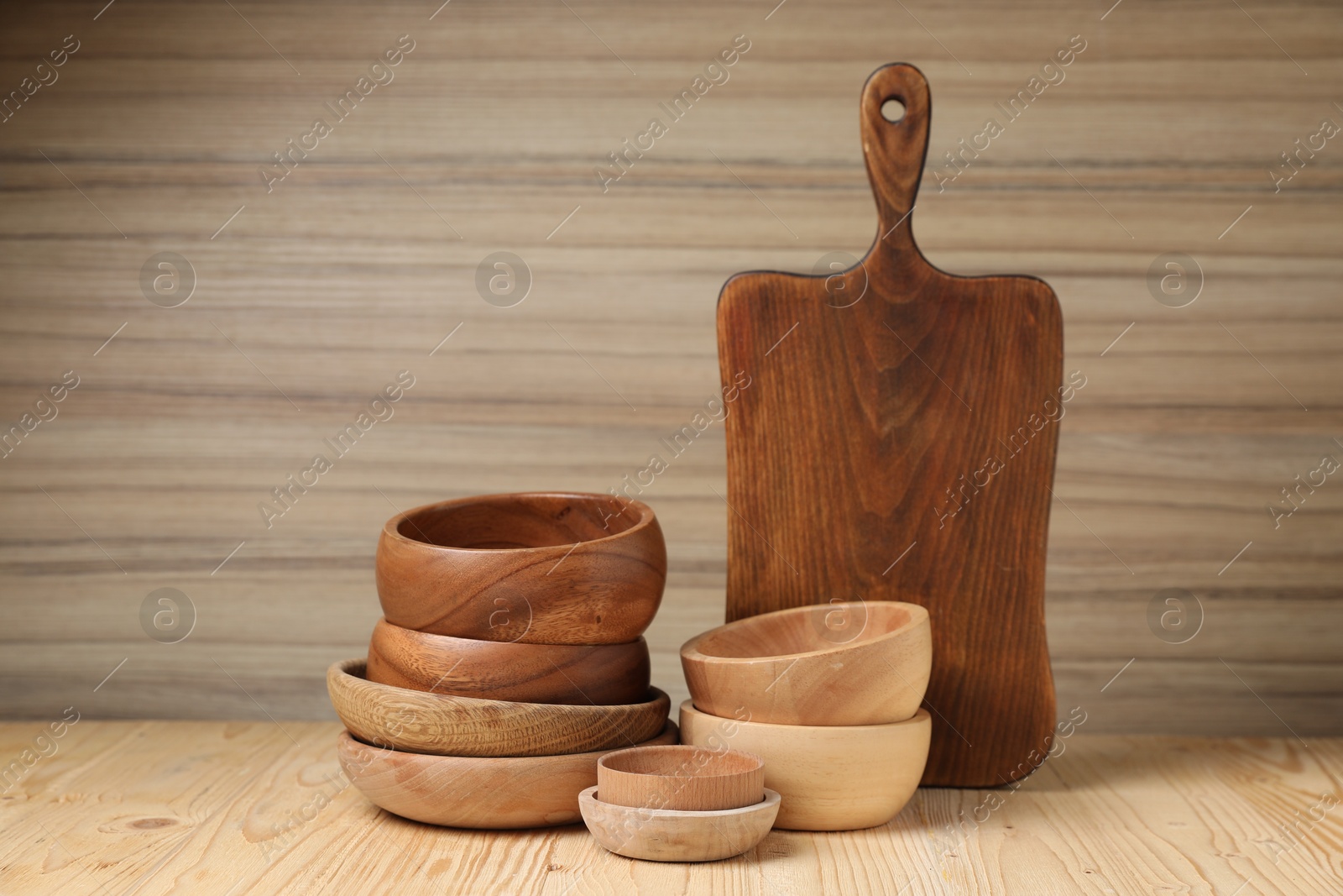 Photo of Bowls and cutting board on wooden table. Cooking utensils