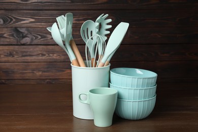 Photo of Dishware and cooking utensils on wooden table