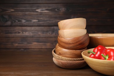 Photo of Bowls with peppers on wooden table, space for text. Cooking utensils