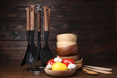 Photo of Dishware, cooking utensils with vegetables and lemon on wooden table