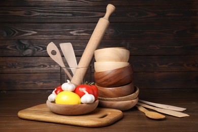 Photo of Dishware, cooking utensils with vegetables and lemon on wooden table