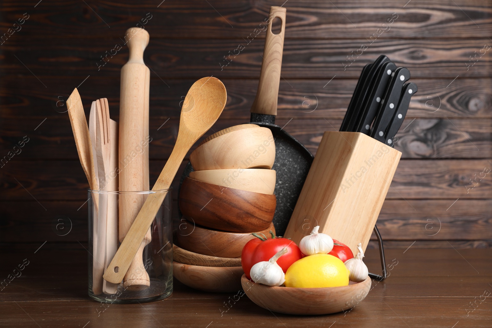 Photo of Dishware, cooking utensils with vegetables and lemon on wooden table