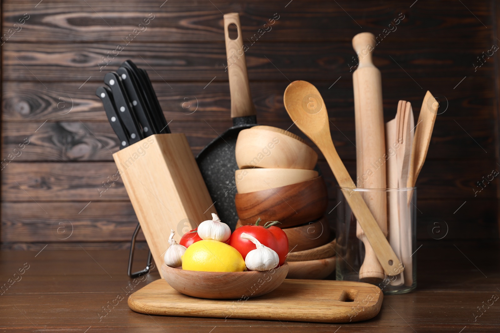 Photo of Dishware, cooking utensils with vegetables and lemon on wooden table