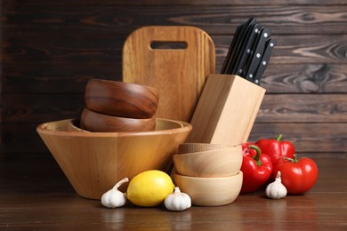 Photo of Dishware, cooking utensils with vegetables and lemon on wooden table