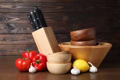 Photo of Dishware, cooking utensils with vegetables and lemon on wooden table