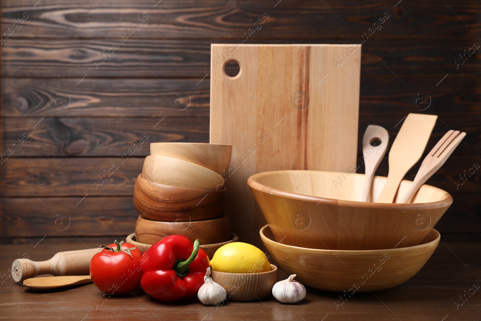 Photo of Dishware, cooking utensils with vegetables and lemon on wooden table