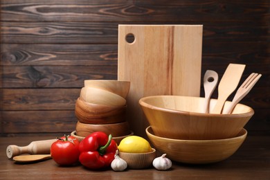 Dishware, cooking utensils with vegetables and lemon on wooden table