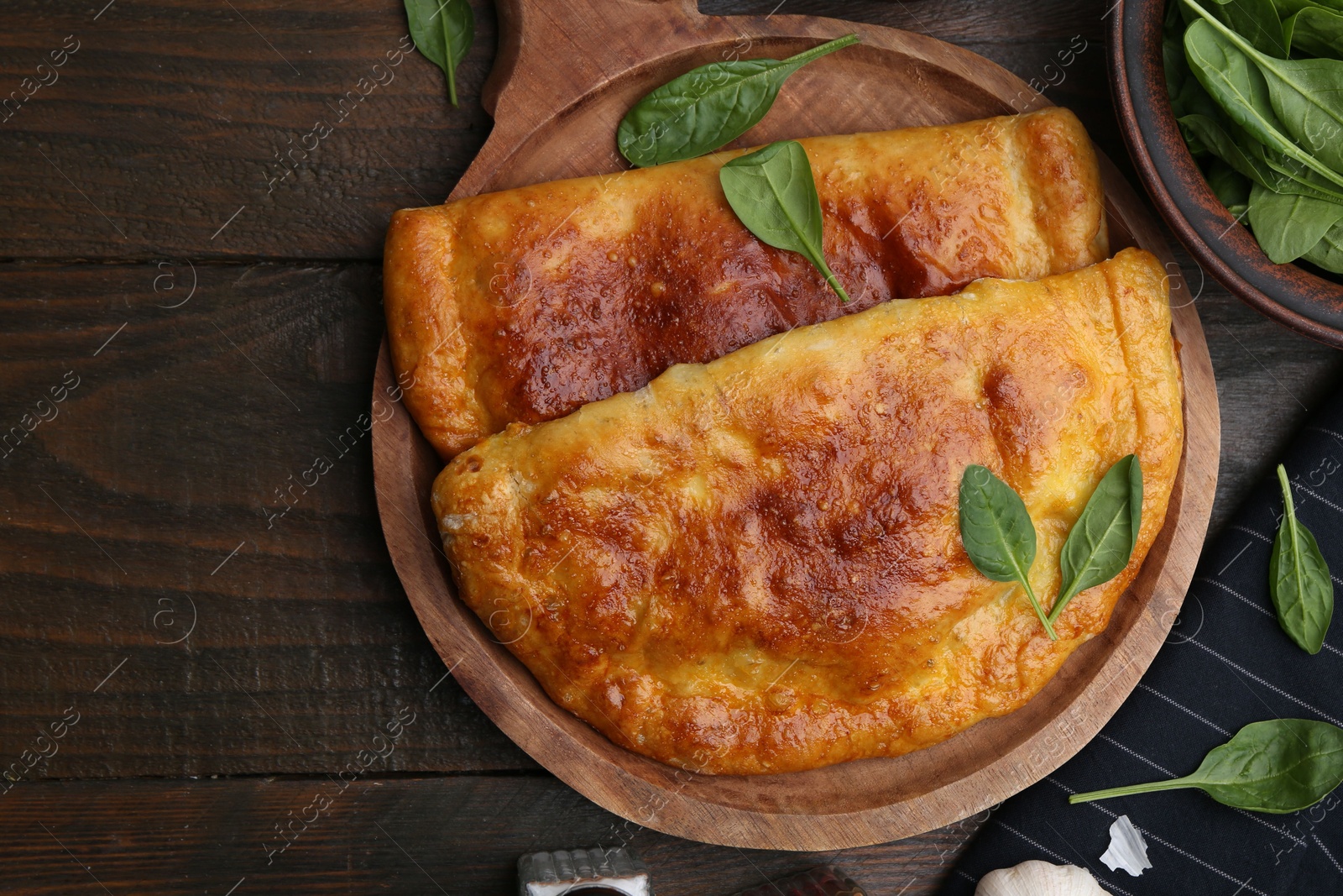 Photo of Tasty calzones with basil on wooden table, top view