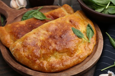 Photo of Tasty calzones with basil on table, closeup