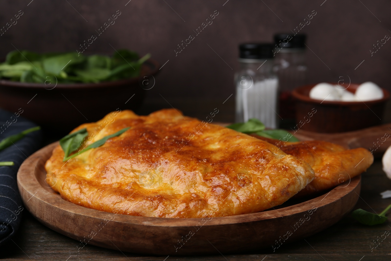 Photo of Tasty calzones with basil on wooden table, closeup