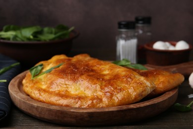 Photo of Tasty calzones with basil on wooden table, closeup