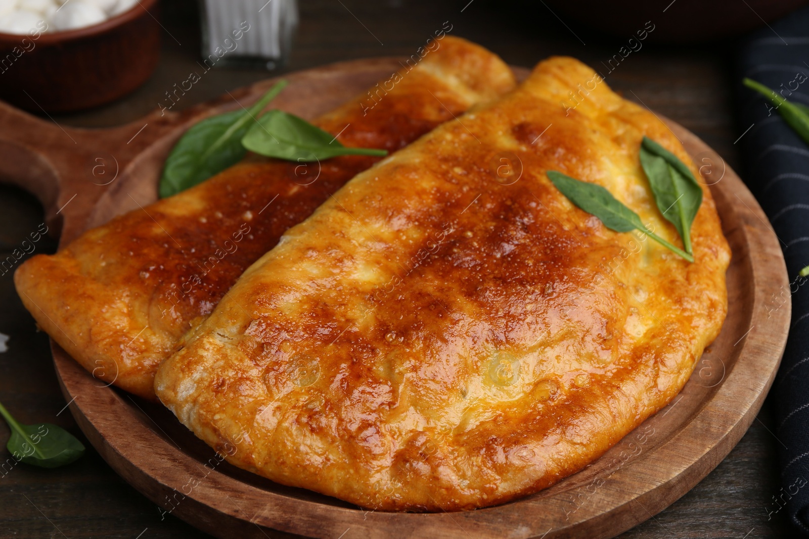 Photo of Tasty calzones with basil on wooden table, closeup