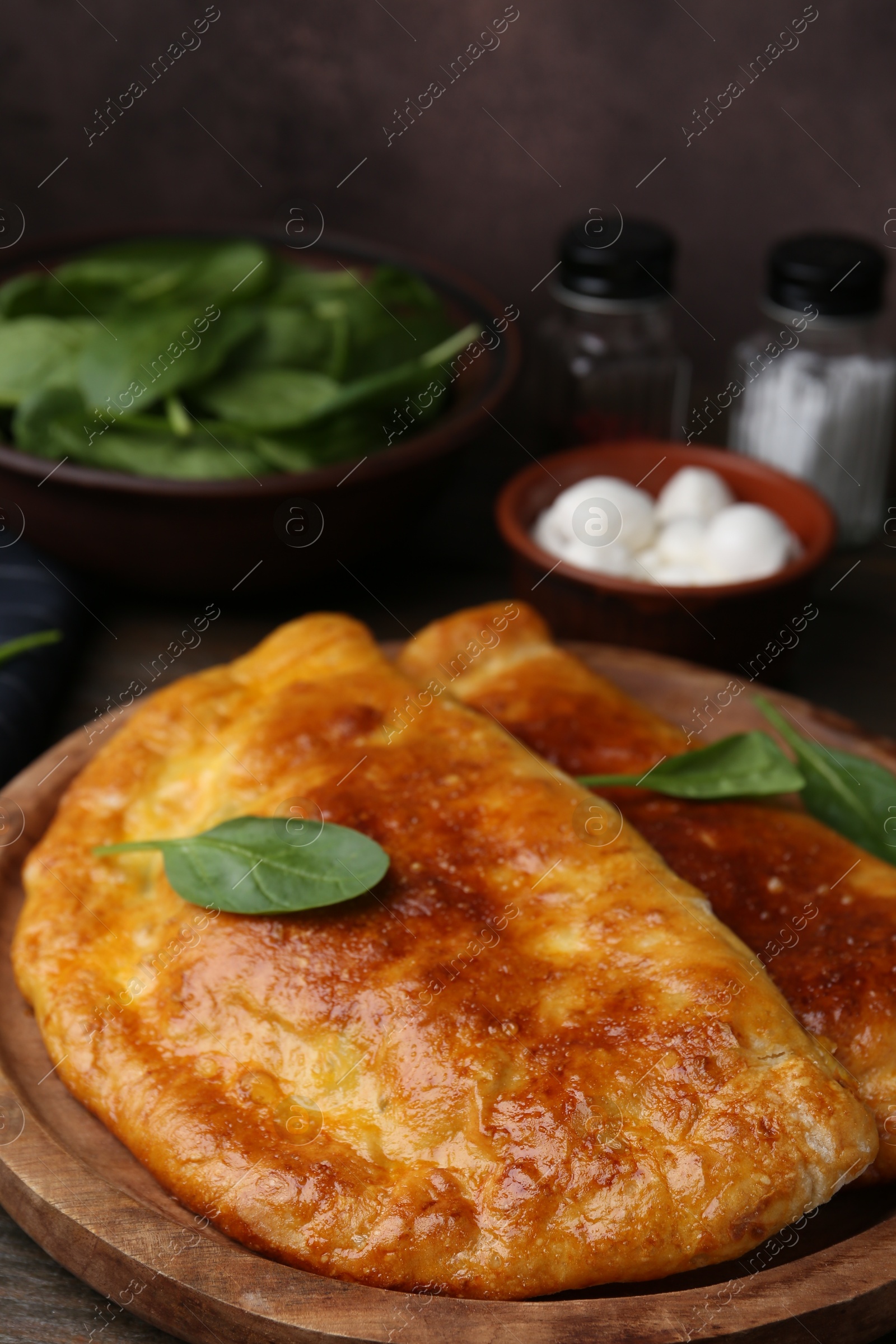 Photo of Tasty calzones with basil and mozzarella cheese on table, closeup