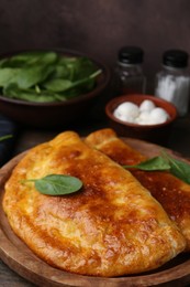 Photo of Tasty calzones with basil and mozzarella cheese on table, closeup