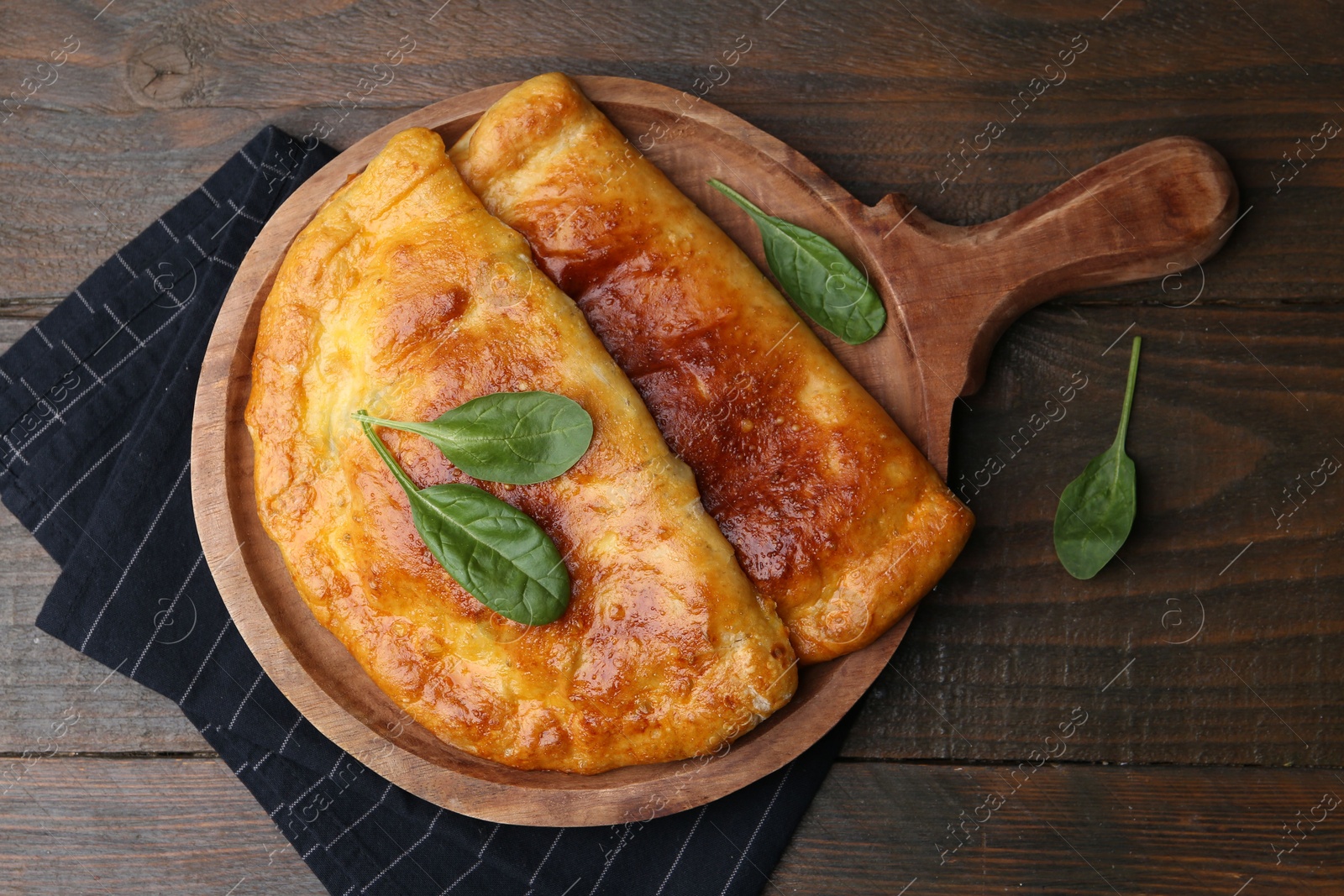 Photo of Tasty calzones with basil on wooden table, top view