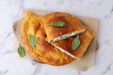 Photo of Tasty calzones with cheese and basil on white marble table, top view