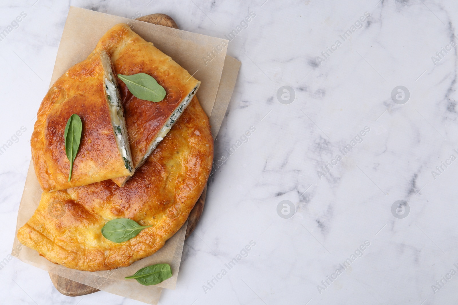 Photo of Tasty calzones with cheese and basil on white marble table, top view. Space for text