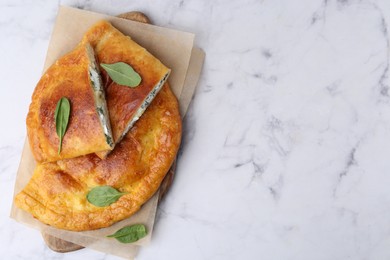 Photo of Tasty calzones with cheese and basil on white marble table, top view. Space for text