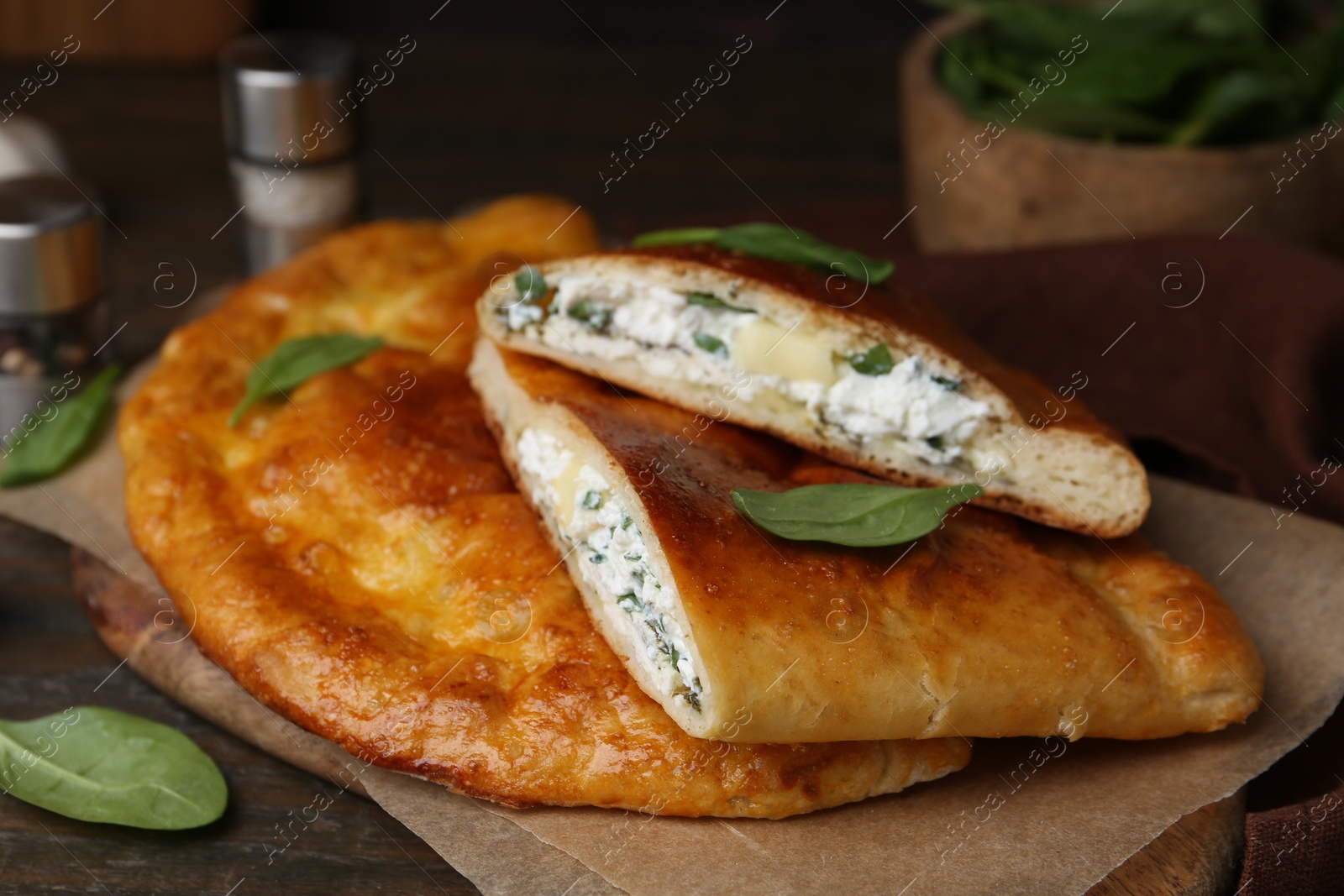 Photo of Tasty calzones with cheese and basil on wooden table, closeup