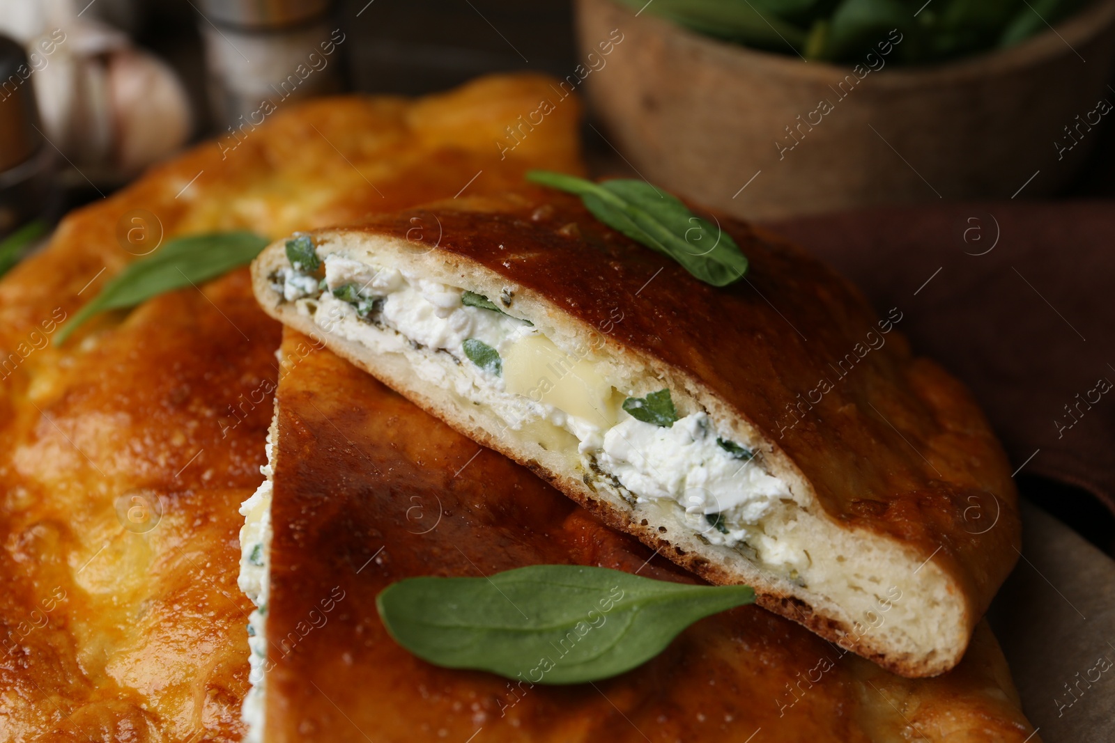 Photo of Tasty calzones with cheese and basil on table, closeup