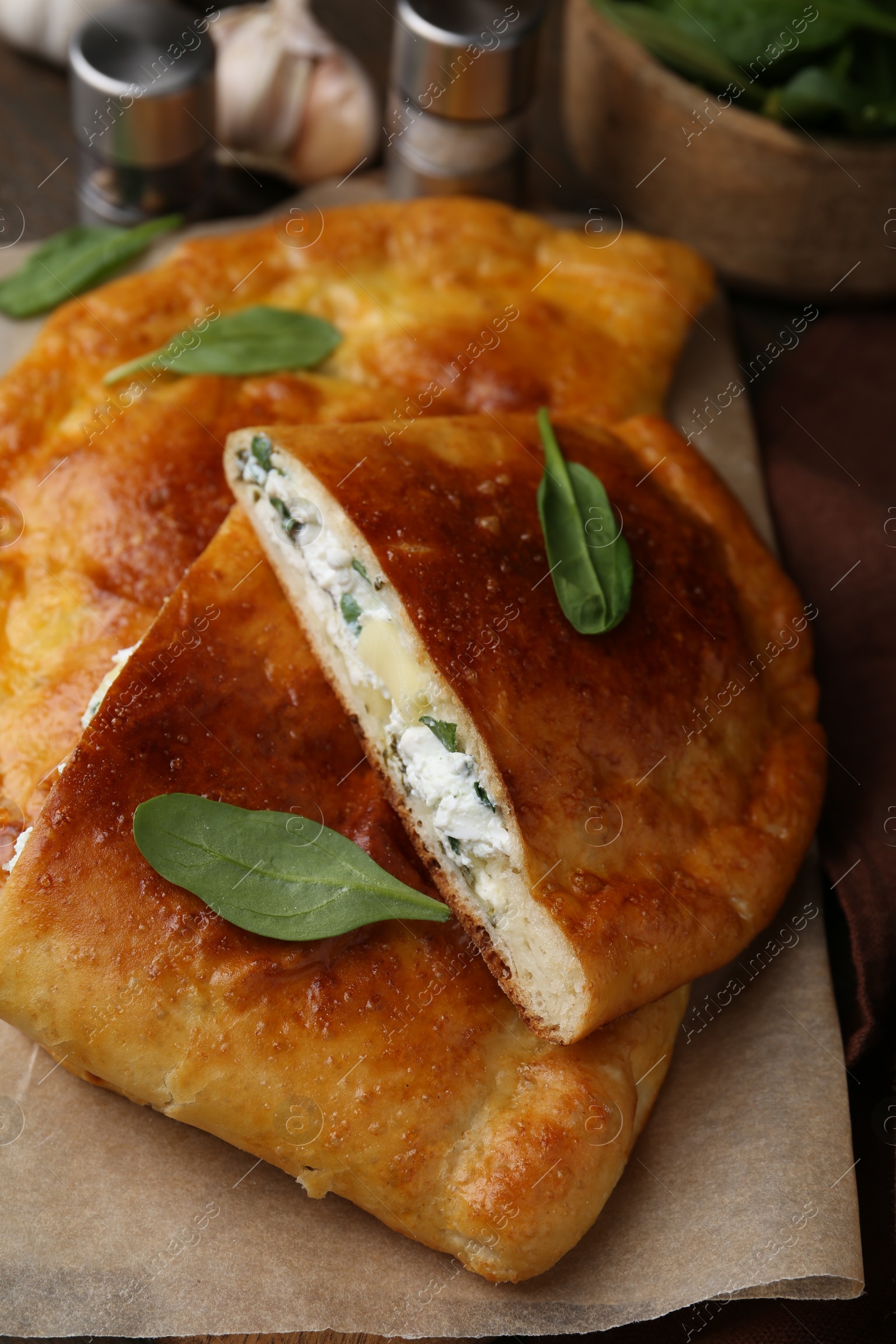 Photo of Tasty calzones with cheese and basil on table, closeup