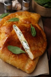 Photo of Tasty calzones with cheese and basil on table, closeup