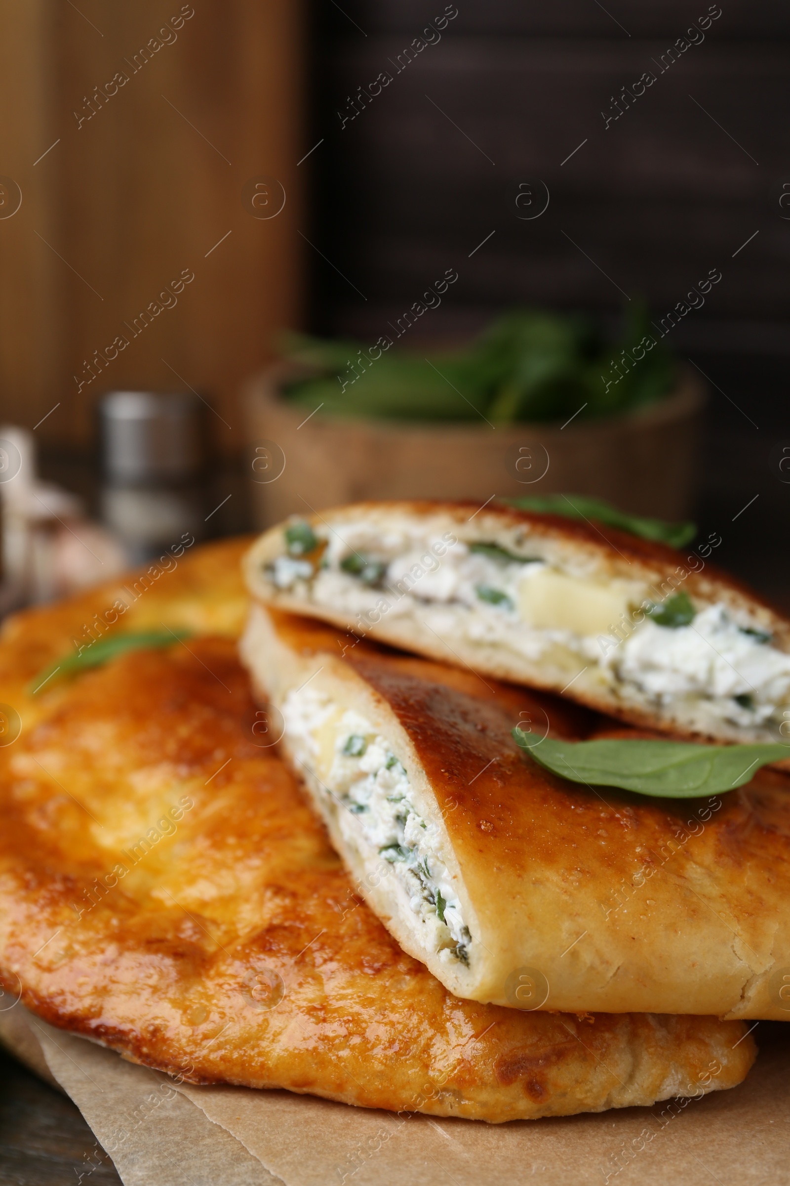 Photo of Tasty calzones with cheese and basil on table, closeup