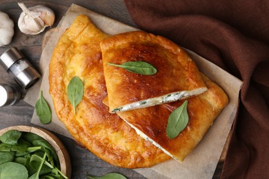 Photo of Tasty calzones with cheese and basil on wooden table, flat lay