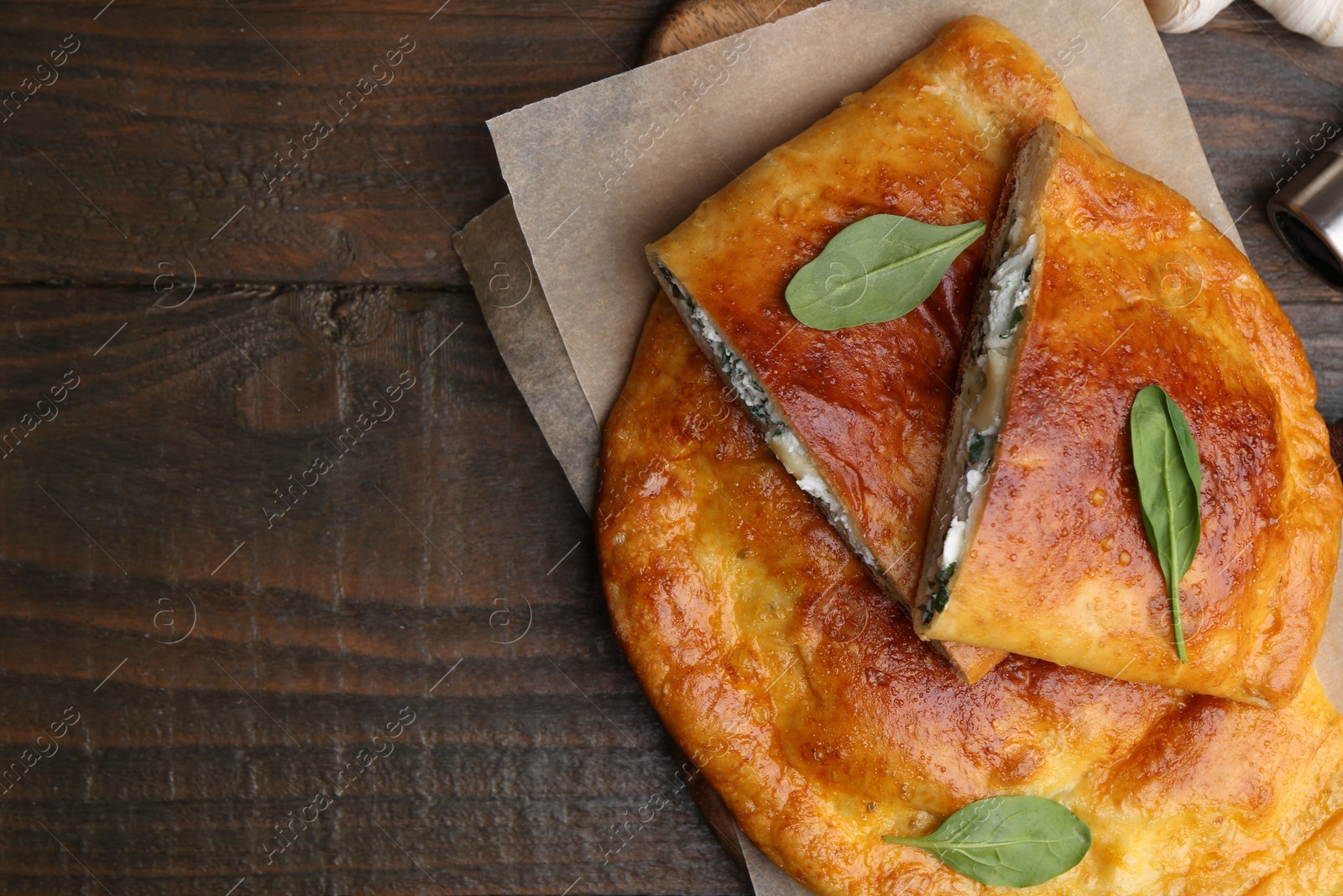 Photo of Tasty calzones with cheese and basil on wooden table, top view. Space for text