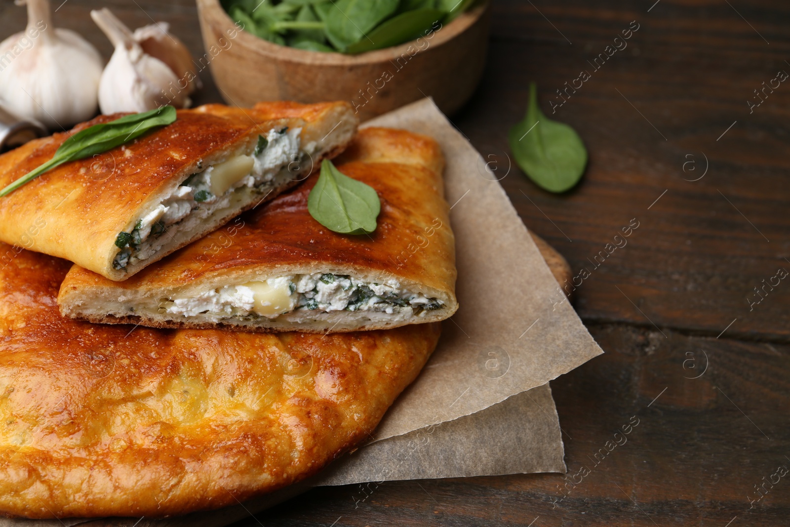 Photo of Tasty calzones with cheese and basil on wooden table, closeup. Space for text