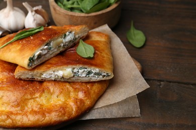 Photo of Tasty calzones with cheese and basil on wooden table, closeup. Space for text