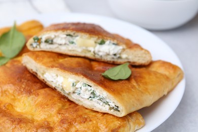 Photo of Tasty calzones with cheese and basil on table, closeup